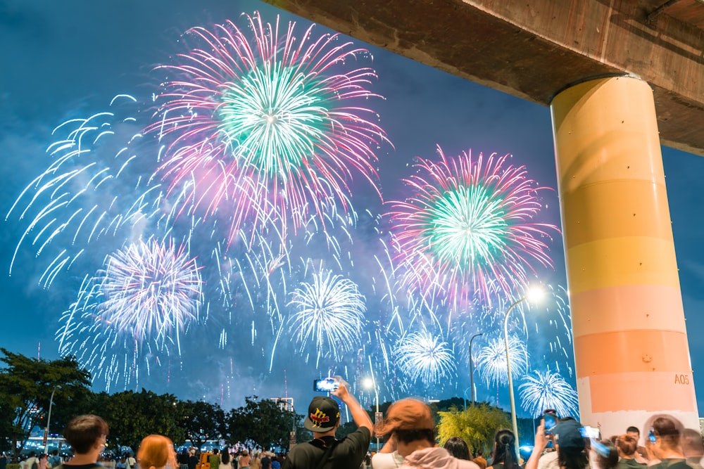 a group of people standing under a bridge watching fireworks