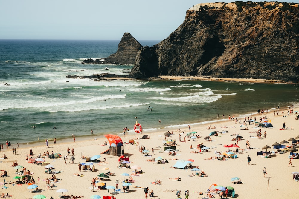 a crowded beach with people and umbrellas on a sunny day