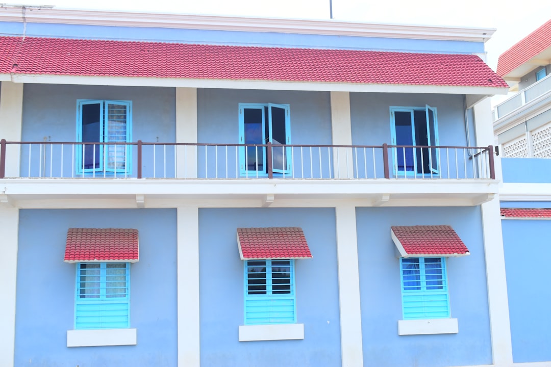 a blue and white building with blue shutters and red roof,
