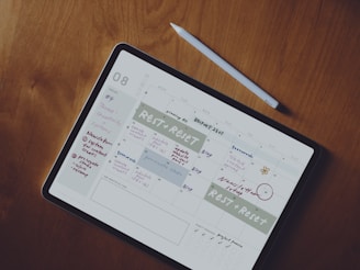 A colorful digital planner open on a tablet screen with handwritten notes and stickers around.