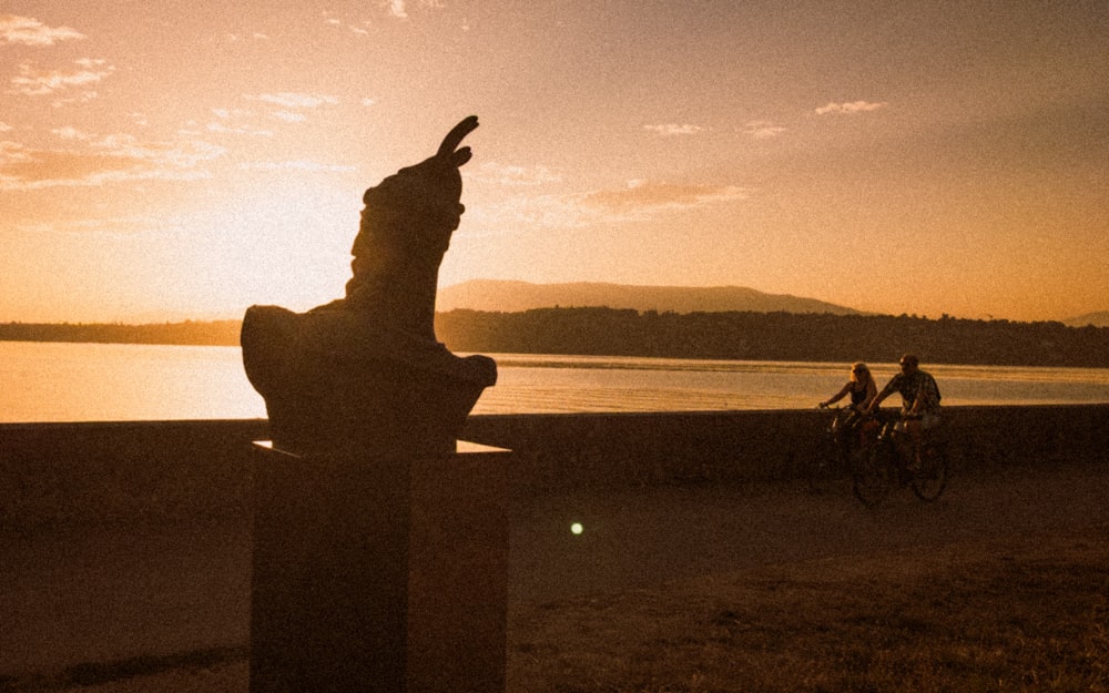 a statue of a person riding a bike next to a body of water