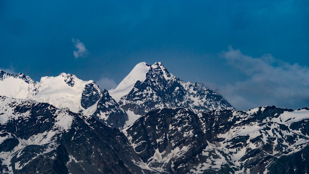 a snow covered mountain range under a blue sky