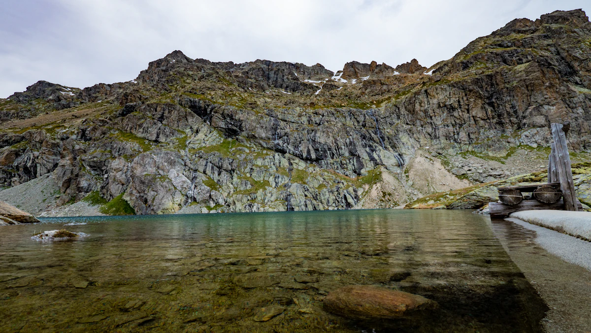 Lej dal Lunghin, a clear mountain lake under grey rock walls near the Lunghin Pass