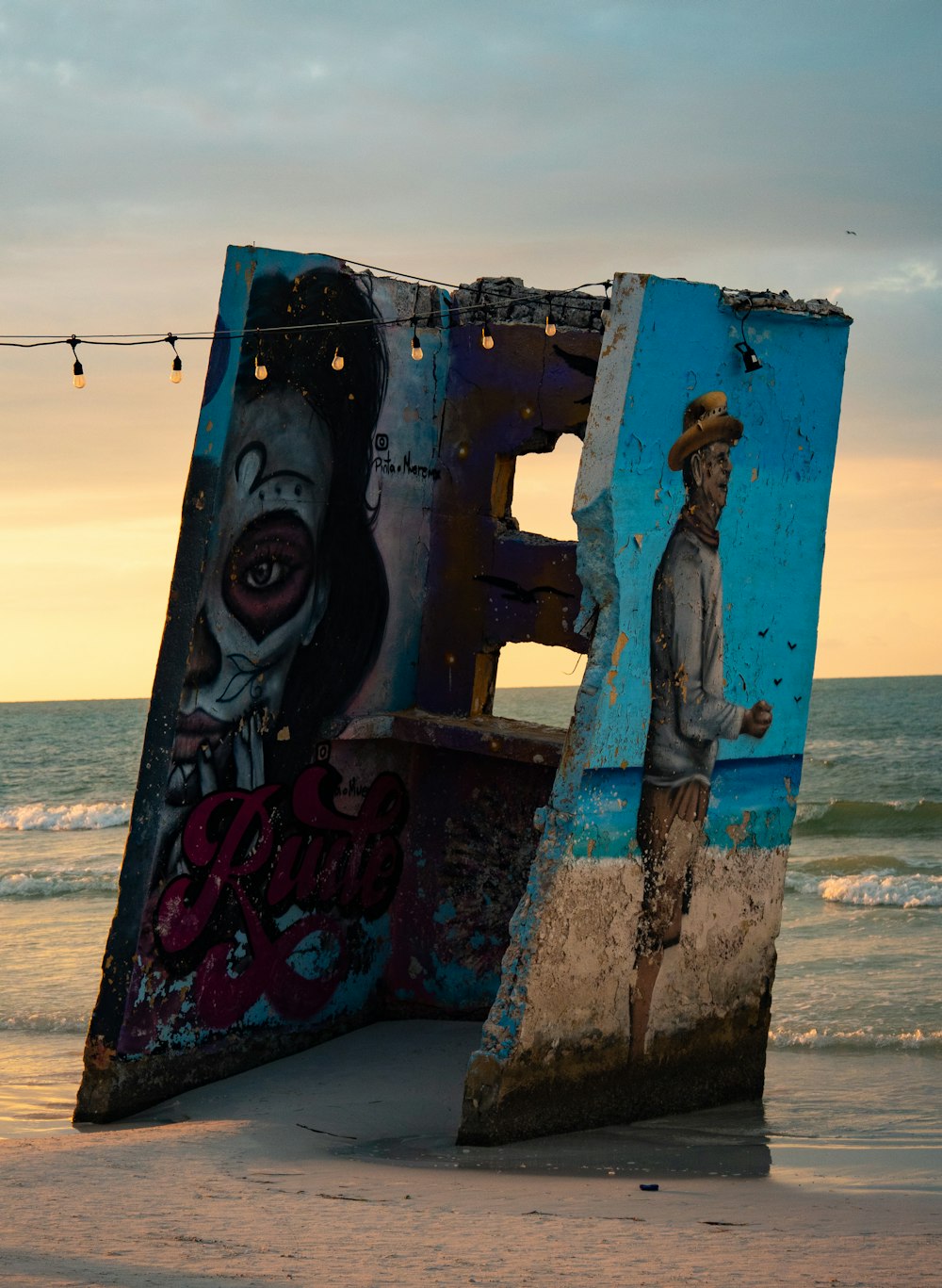 Un hombre parado junto a una gran obra de arte en la playa
