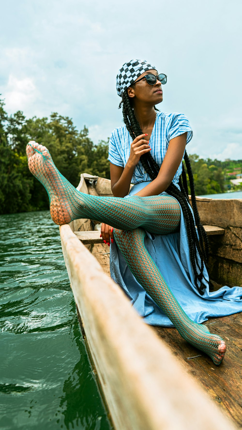a woman in a blue dress sitting on a dock