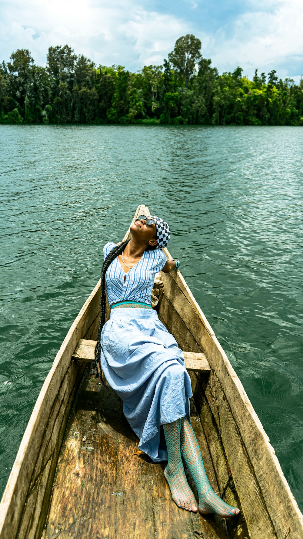 a woman in a blue dress is sitting in a boat