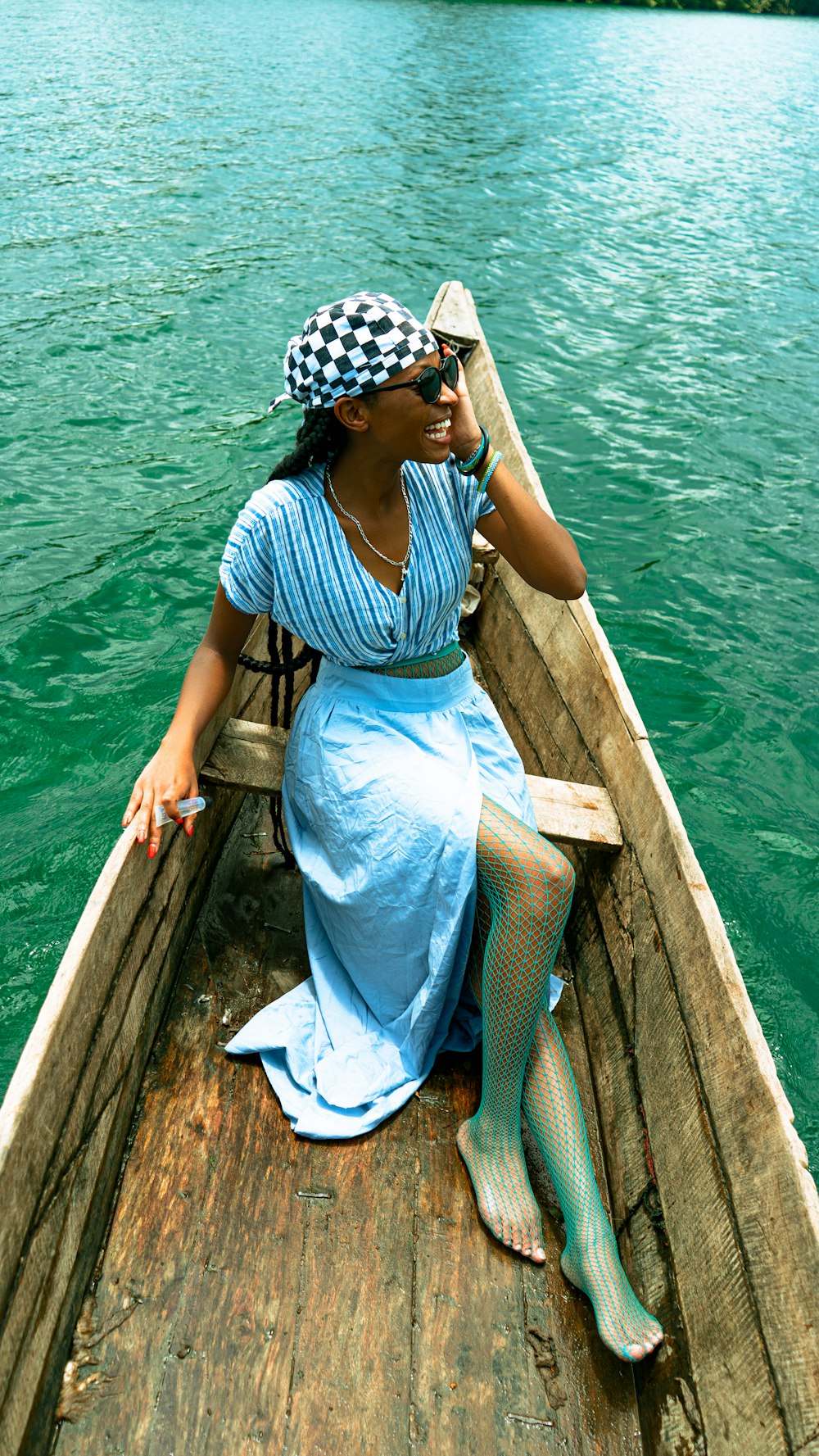 a woman in a blue dress is sitting in a boat