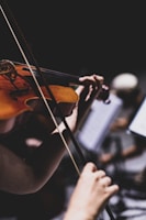 a woman playing a violin in front of a laptop