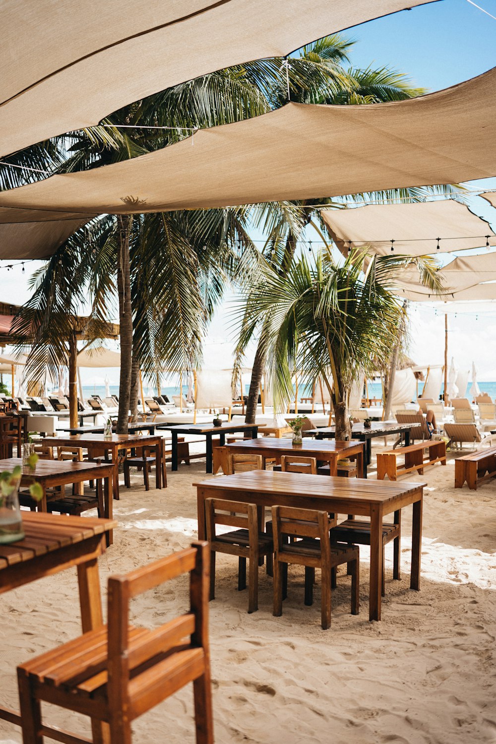 tables and chairs under umbrellas on a sandy beach