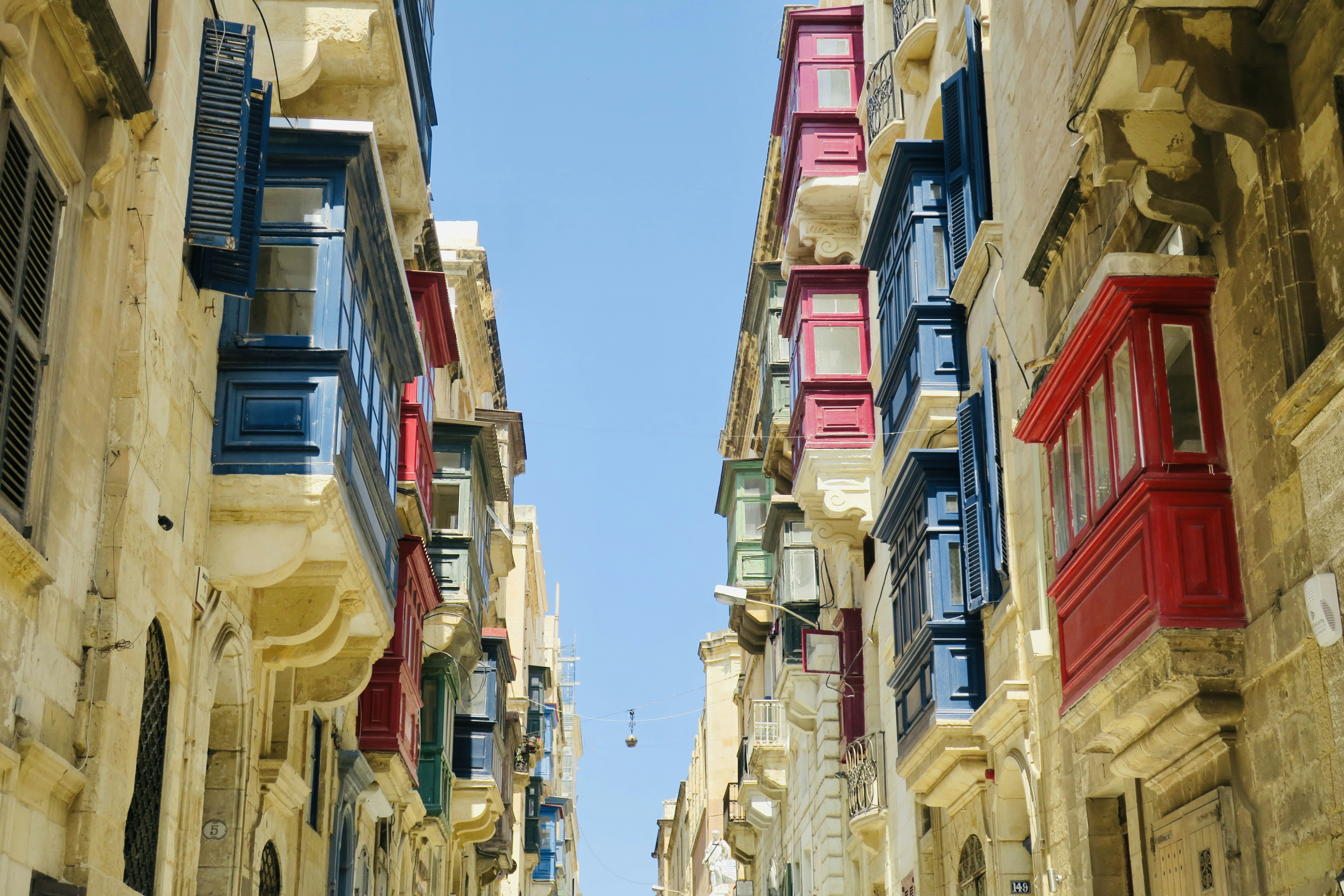a narrow street with many windows and shutters