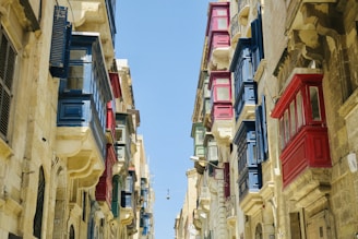 a narrow street with many windows and shutters