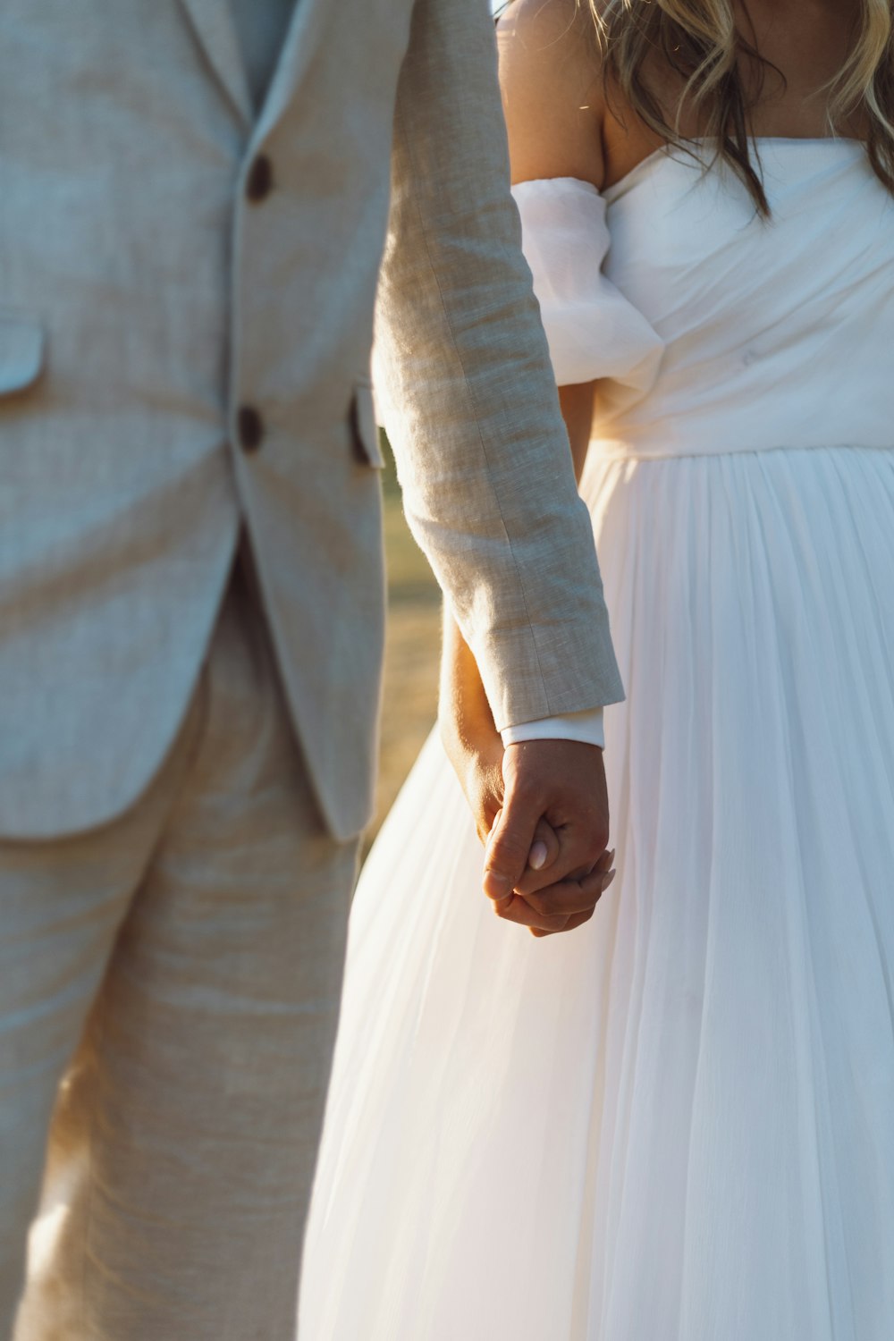 a bride and groom hold hands as they walk together