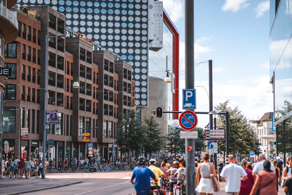 a group of people walking down a street next to tall buildings