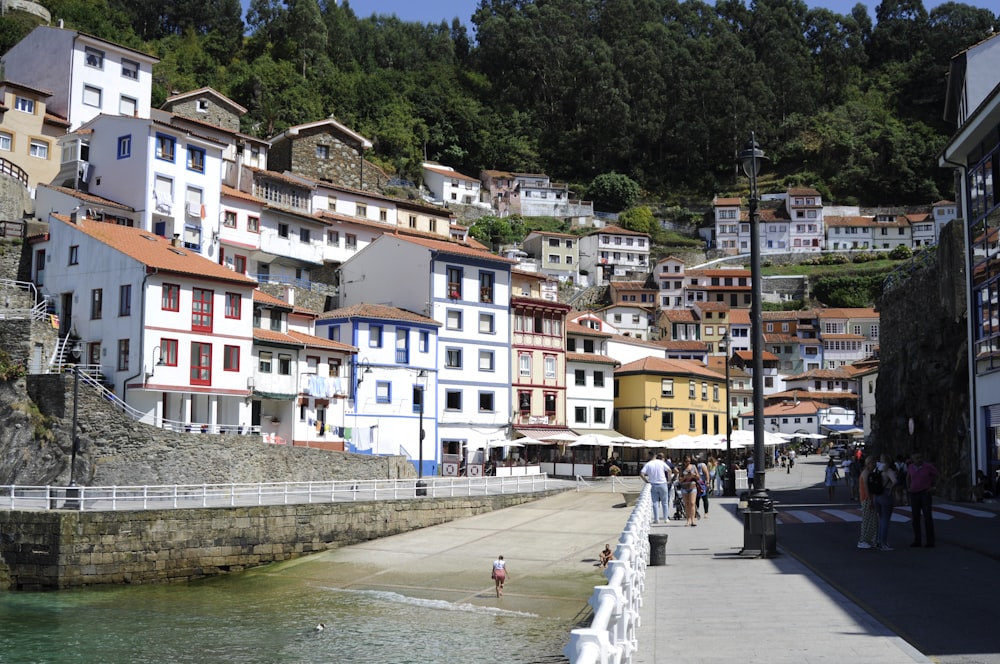 a group of people walking down a sidewalk next to a body of water