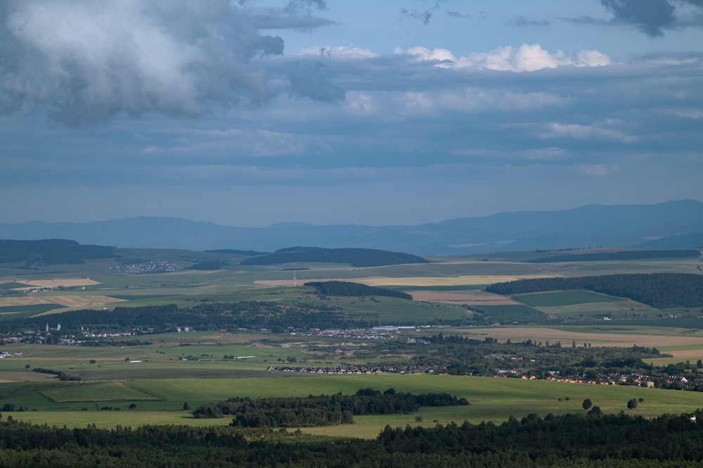 a scenic view of a valley and mountains under a cloudy sky