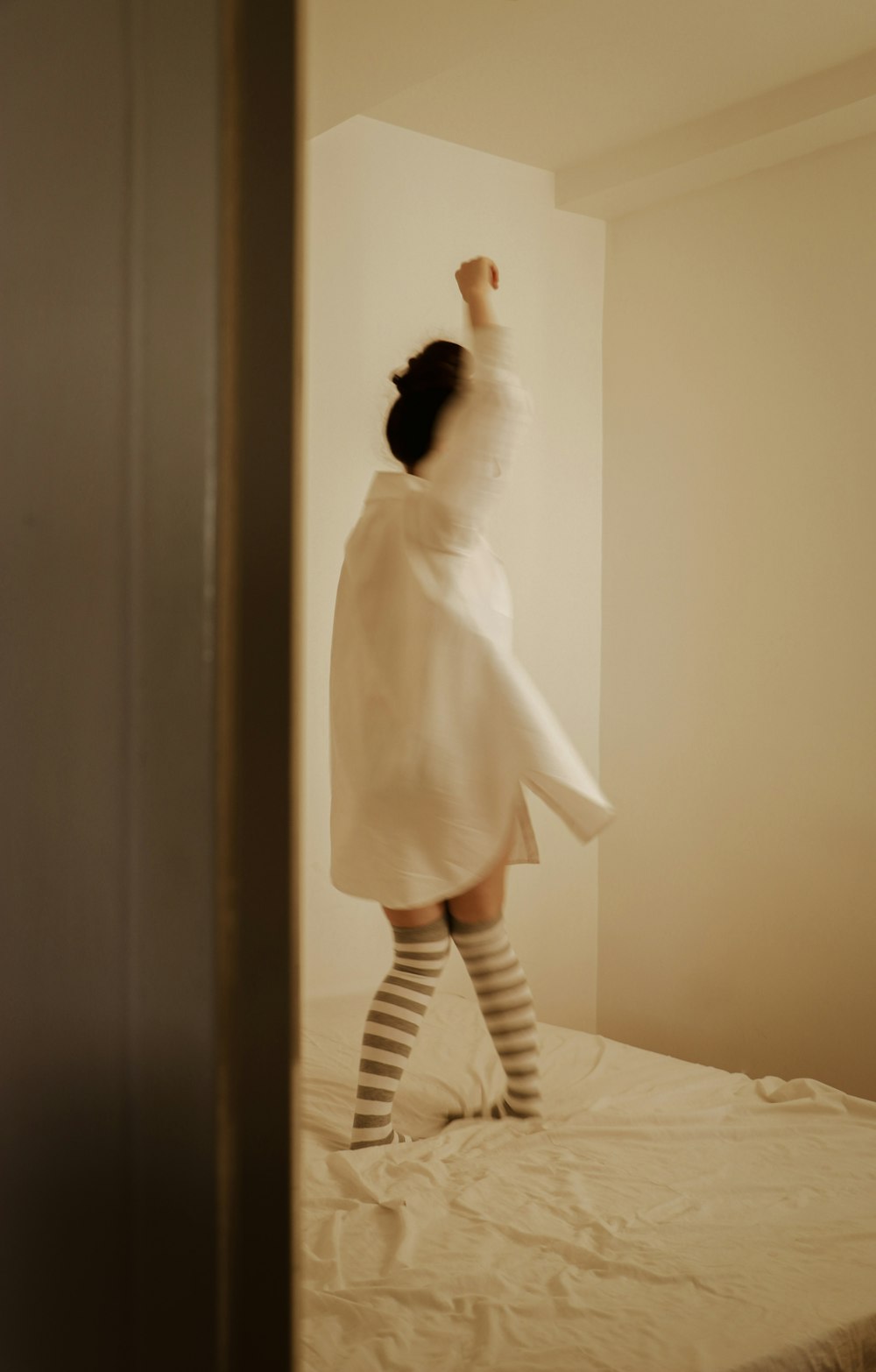 Una mujer con un vestido blanco está parada en una cama