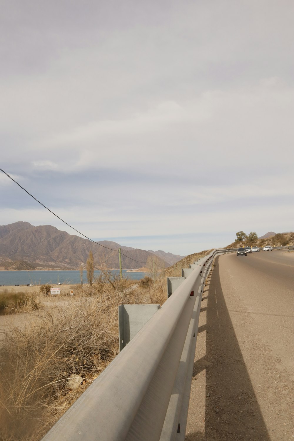 a road with a fence and a body of water in the background