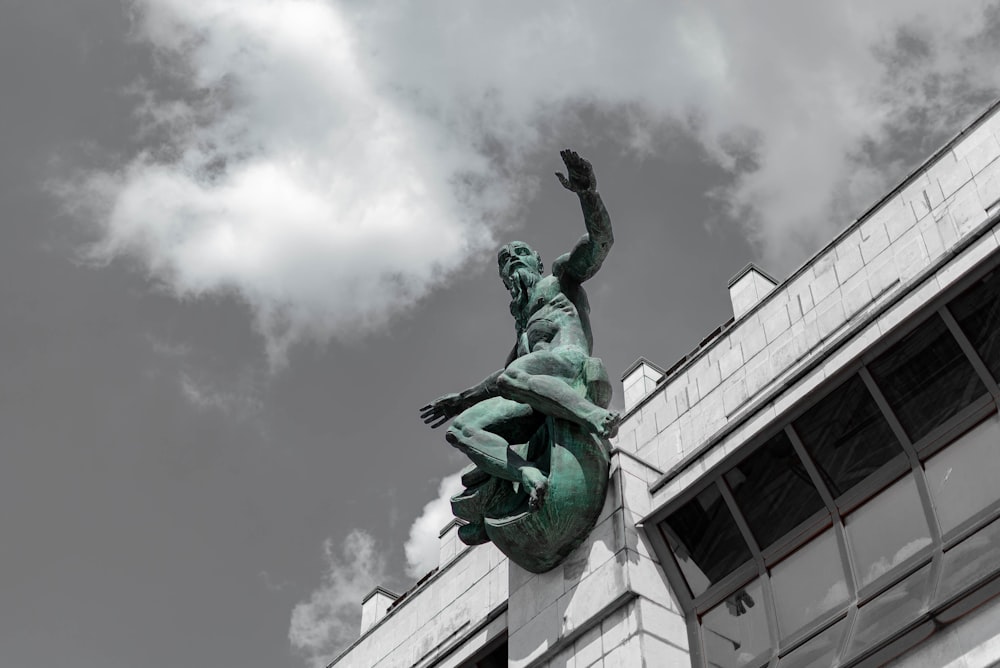 a statue of a man holding a fish on top of a building