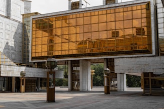 Modern architectural concrete building with large glass panels and subtle champagne gold accents.