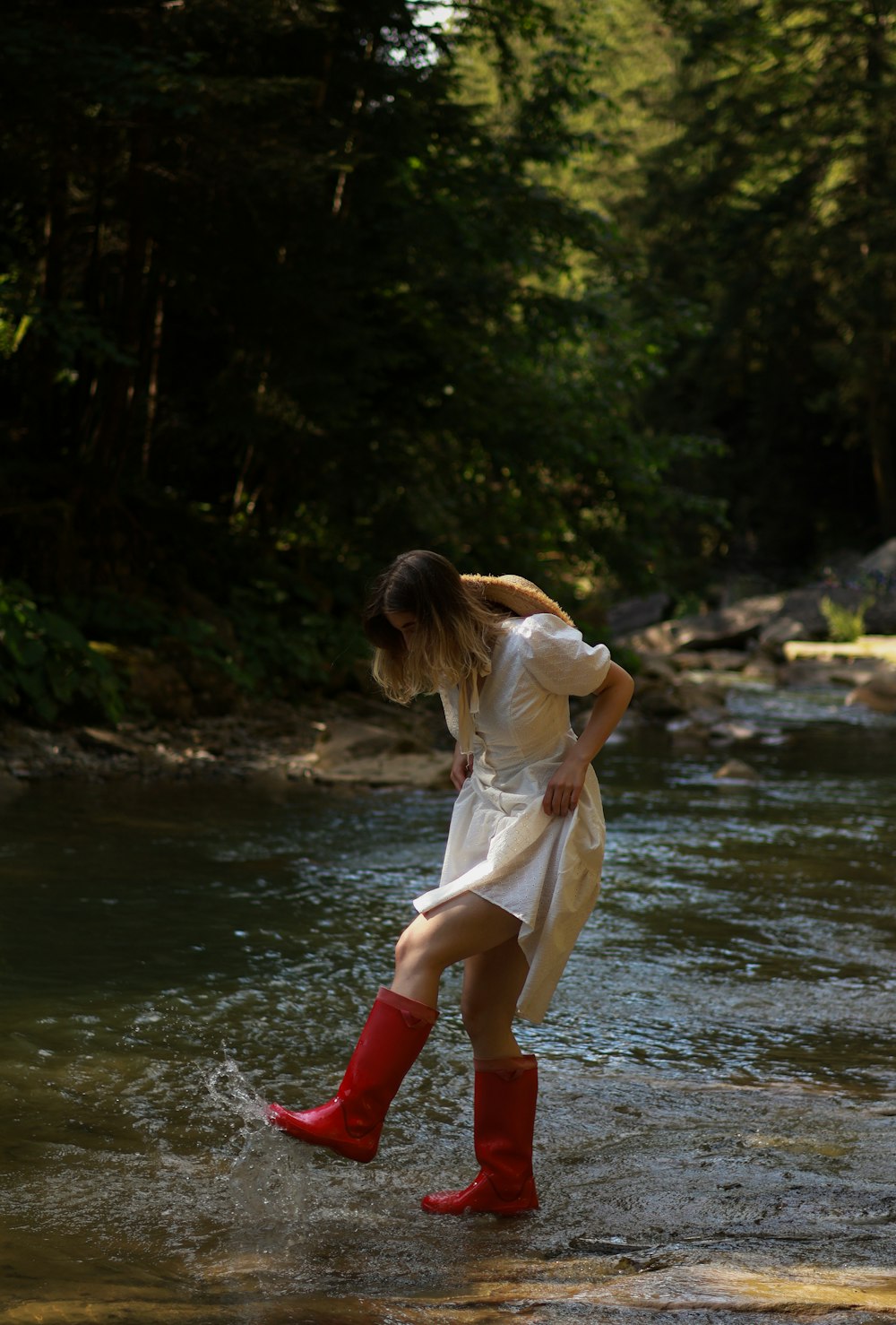 a woman in red boots is standing in the water
