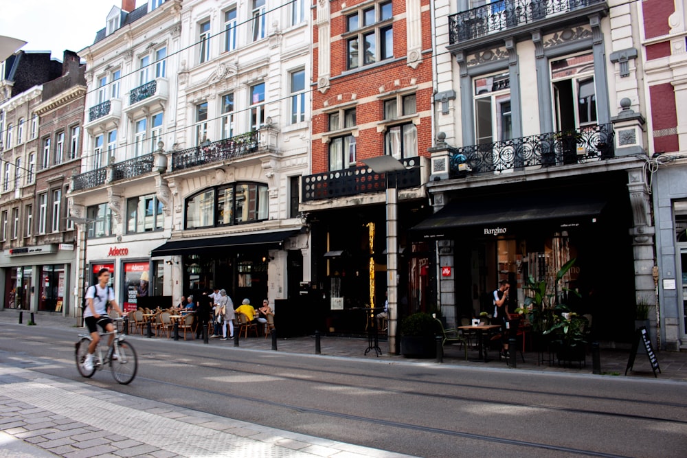 Un hombre montando en bicicleta por una calle junto a edificios altos