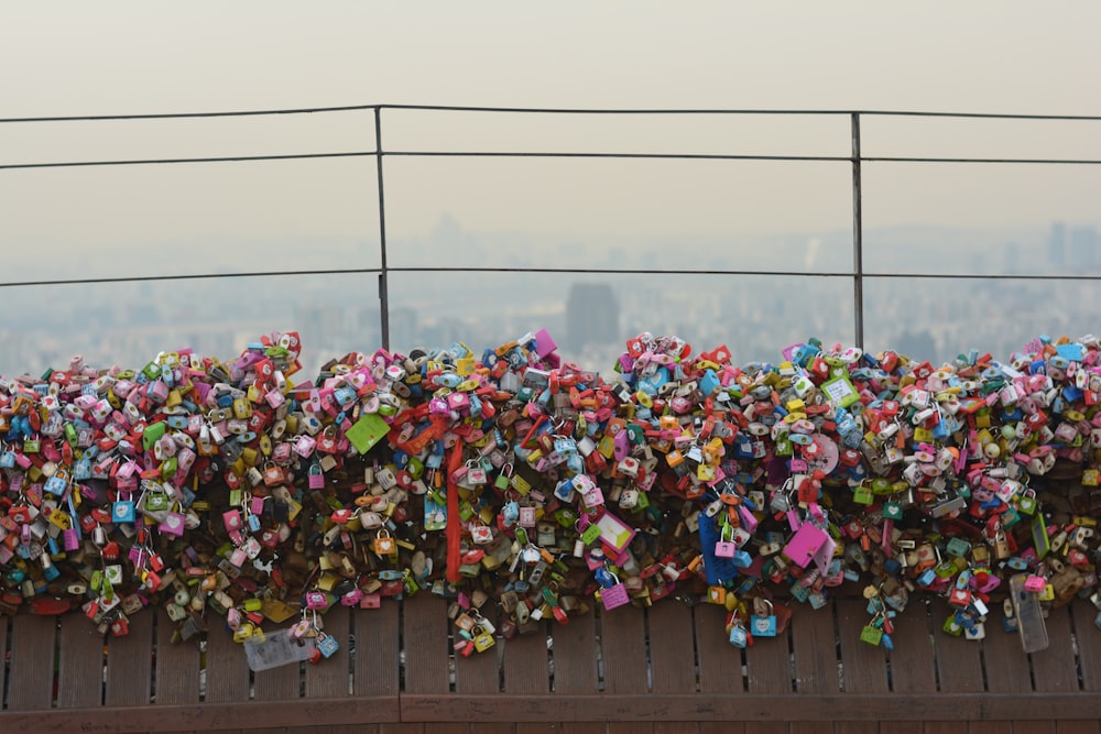 a fence covered in padlocks with a city in the background