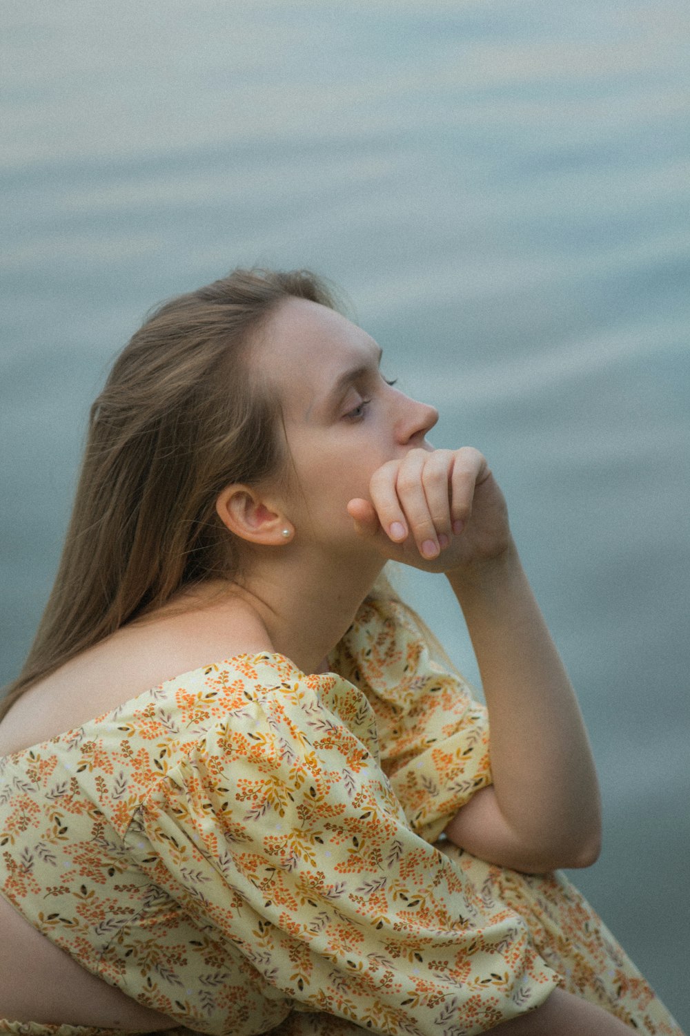 a young girl sitting on the edge of a body of water