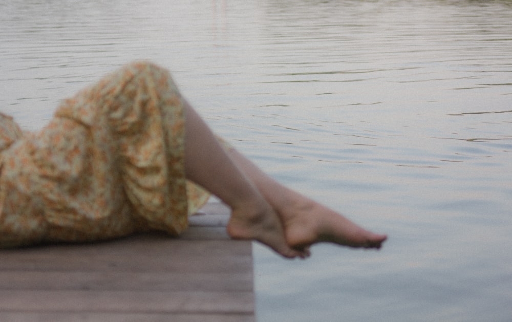 a woman laying on a dock next to a body of water