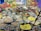 A large assortment of traditional Indian sweets and savories arranged on a table. There are numerous bowls and plates filled with various kinds of snacks, each crafted with care and arranged in an inviting manner. The backdrop includes colorful paintings of cattle against a backdrop of rocks and flowers.