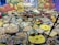 A large assortment of traditional Indian sweets and savories arranged on a table. There are numerous bowls and plates filled with various kinds of snacks, each crafted with care and arranged in an inviting manner. The backdrop includes colorful paintings of cattle against a backdrop of rocks and flowers.
