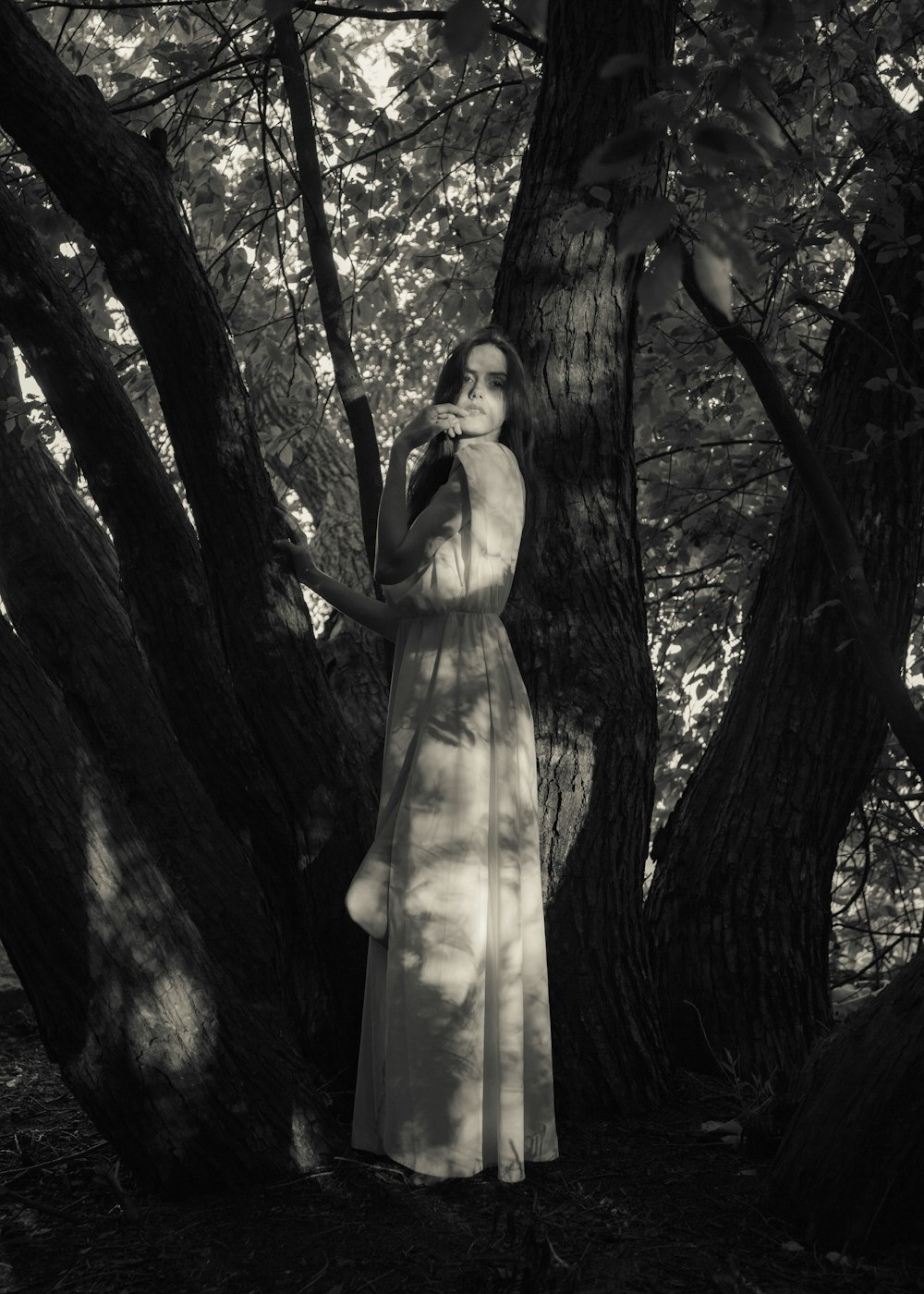 a woman in a white dress standing in front of a tree