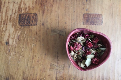 A bowl of dried hibiscus flowers on a wooden table.