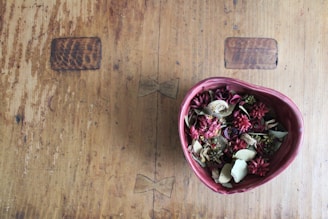 A bowl of dried hibiscus flowers on a wooden table.