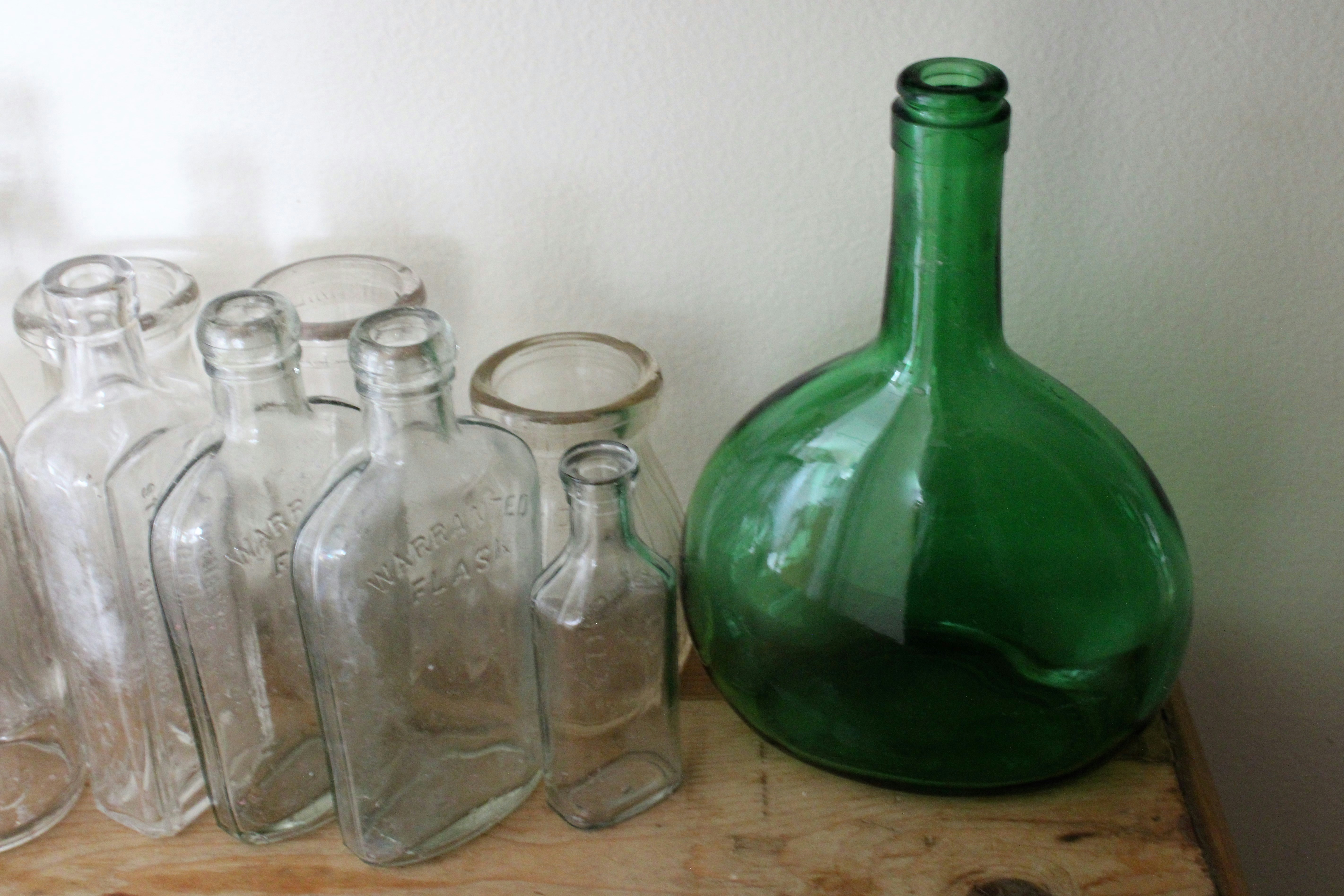 A green glass bottle sitting on top of a wooden table