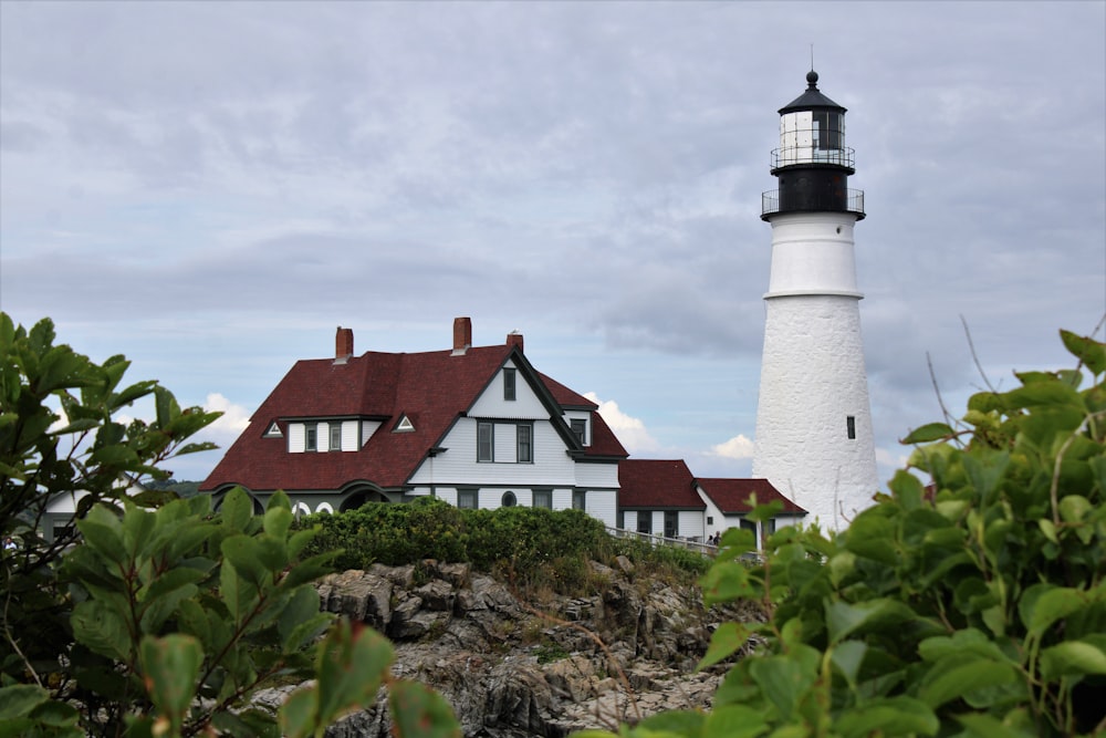 a white and black lighthouse with a red roof