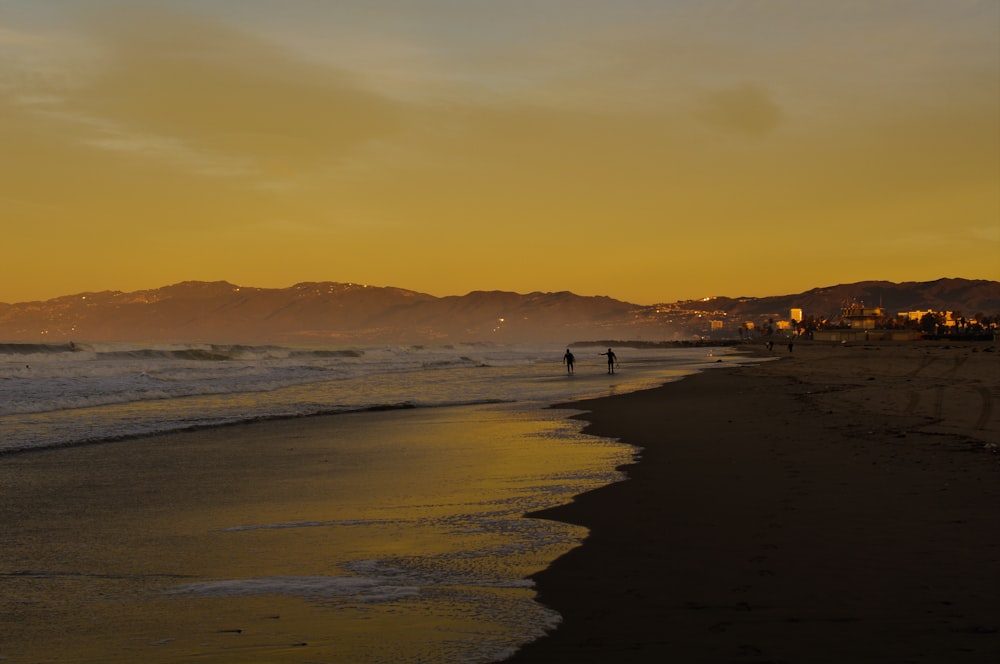 Un couple de personnes debout au sommet d’une plage de sable