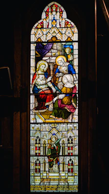 Historic stained glass window depicting a sacred scene.