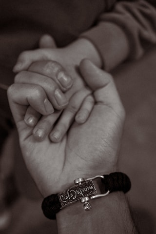 Close-up of hands gently holding a leather cuff, highlighting trust and care.