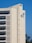 A tall beige building with rectangular windows and a large 'BCI' logo with a leaf symbol on the side. The building is set against a clear blue sky with some trees visible at the bottom right corner.