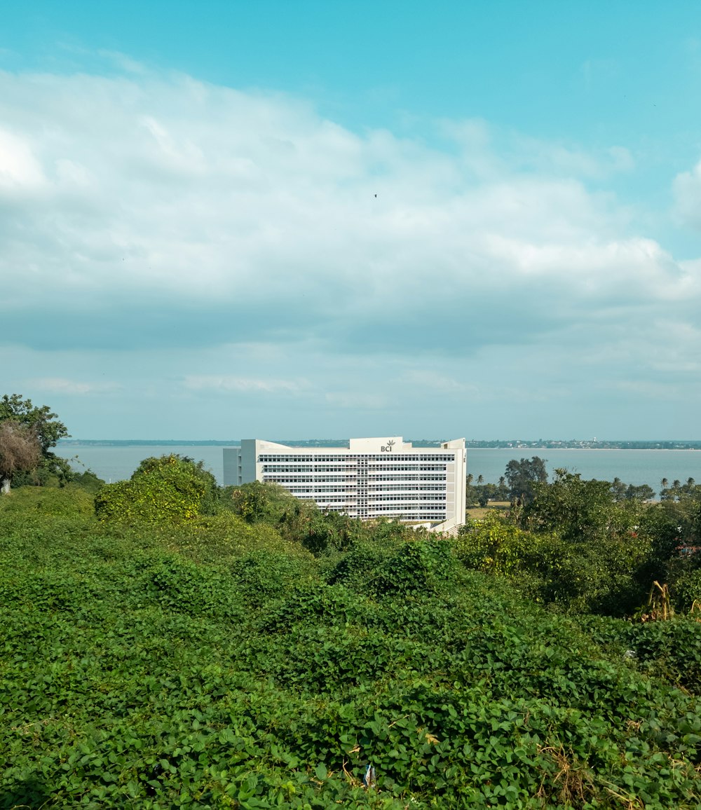 a large white building sitting on top of a lush green hillside