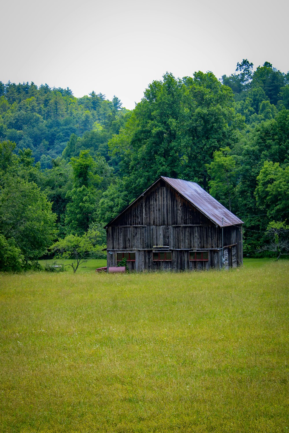 a barn in a field with trees in the background