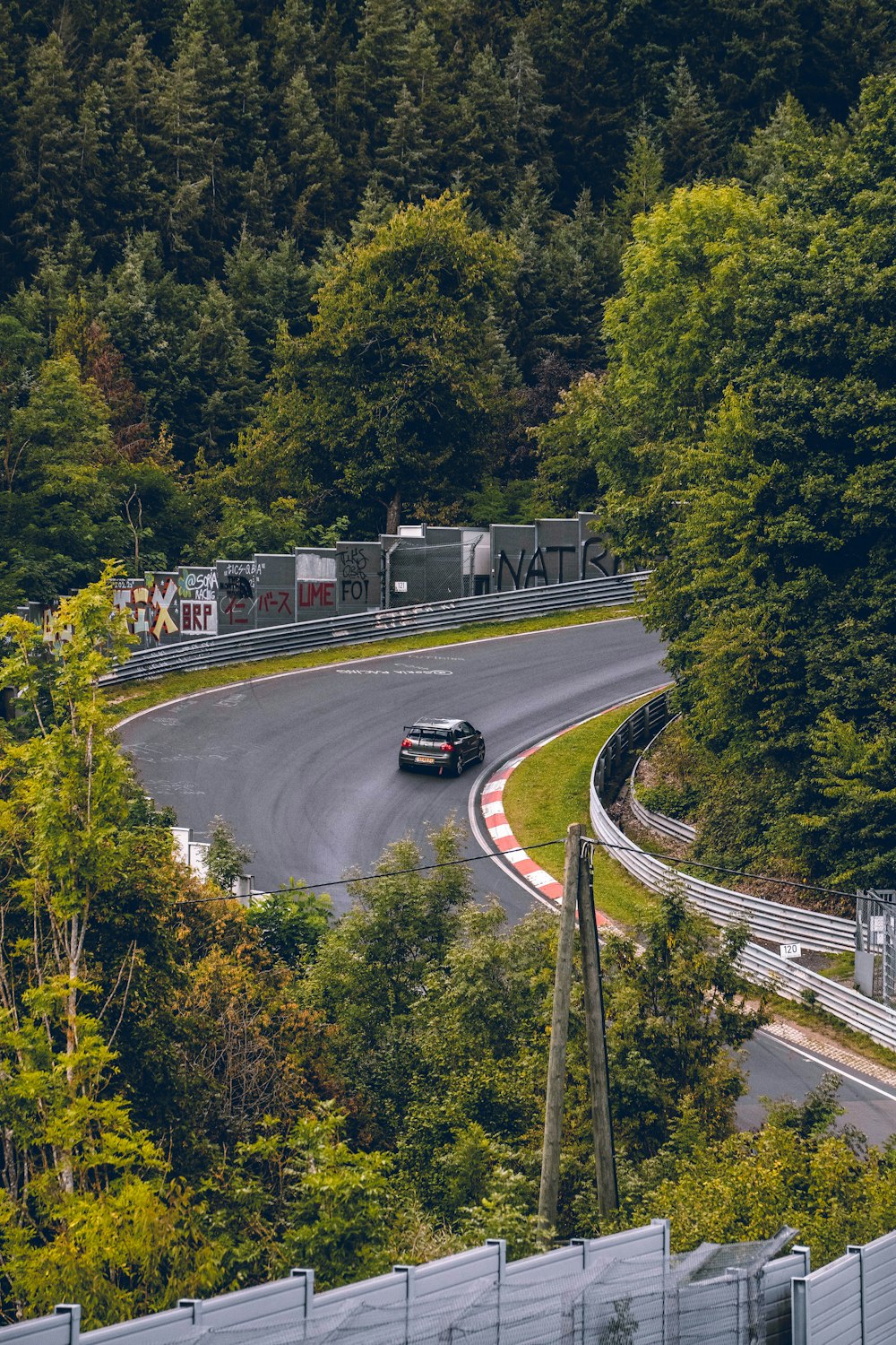 a car driving down a winding road surrounded by trees