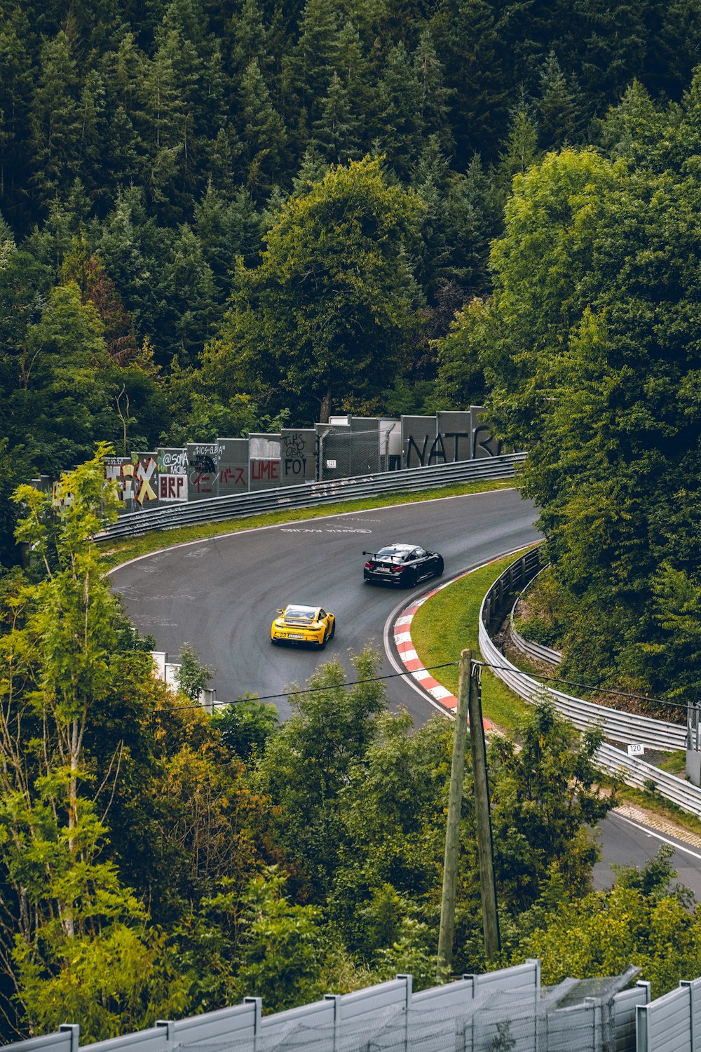 a couple of cars driving down a winding road