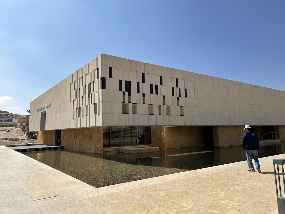 a man standing in front of a building next to a body of water