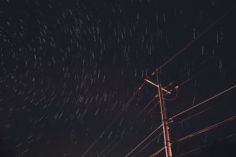 a telephone pole with a sky full of stars in the background