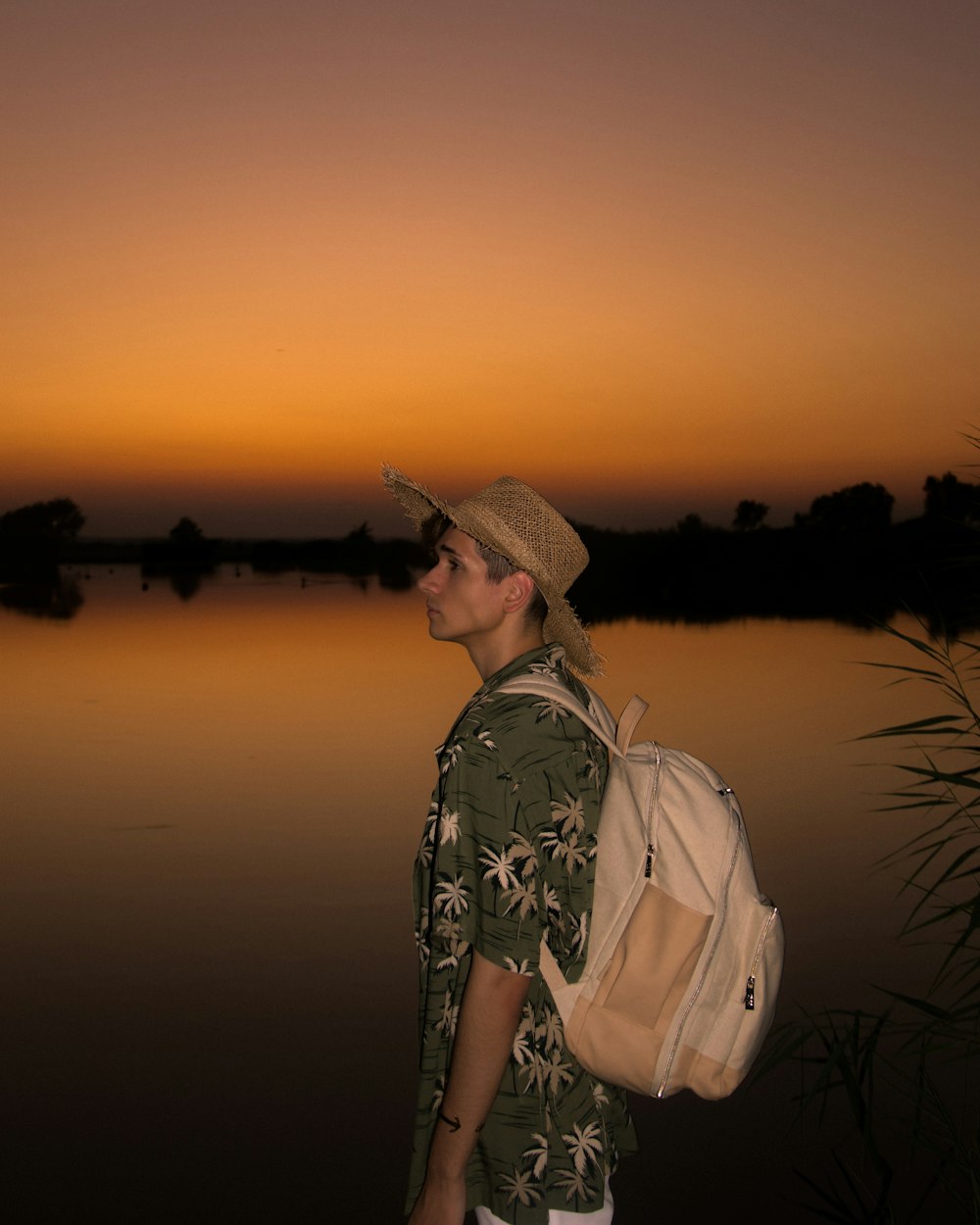 a man with a backpack standing in front of a body of water