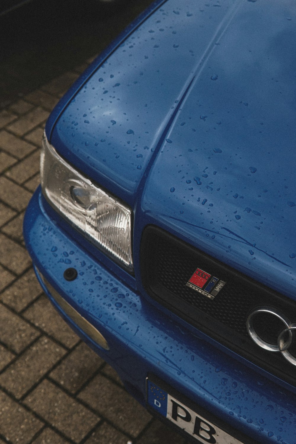 a close up of a blue car with rain drops on it