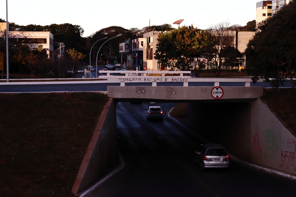 a car driving under a bridge with graffiti on it