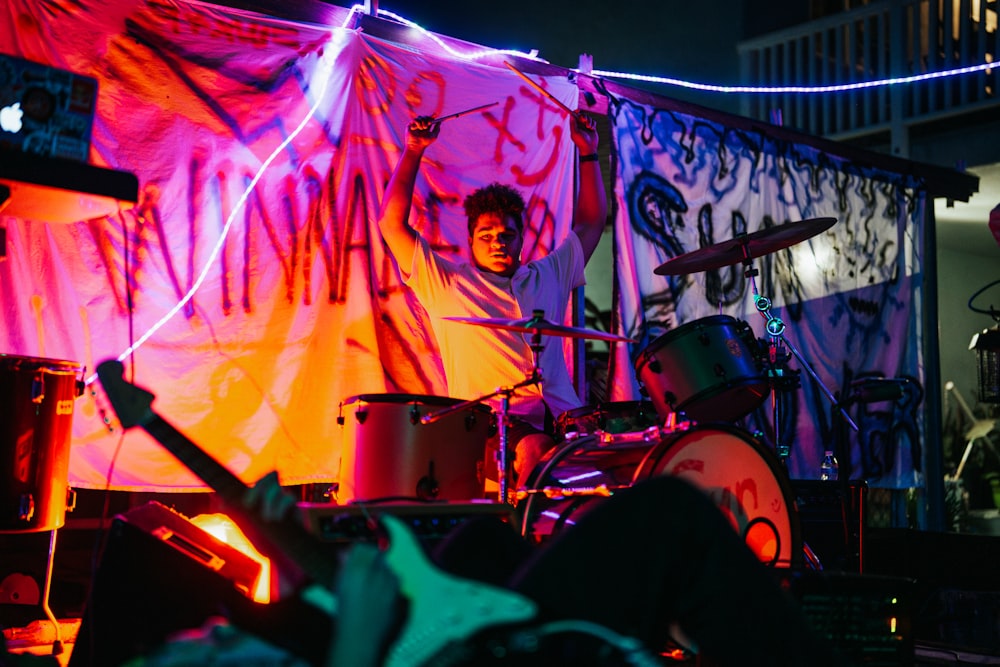 a man playing drums in front of a stage