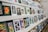 A collection of framed photographs displayed on shelves. The images include a variety of subjects like flowers, nature scenes, and animals. The arrangement is orderly, with photographs leaning against the wall.